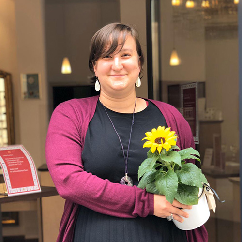 Schmuckkontor Koblenz Außenansicht - Verkäuferin mit Blume in der Hand vor der Tür